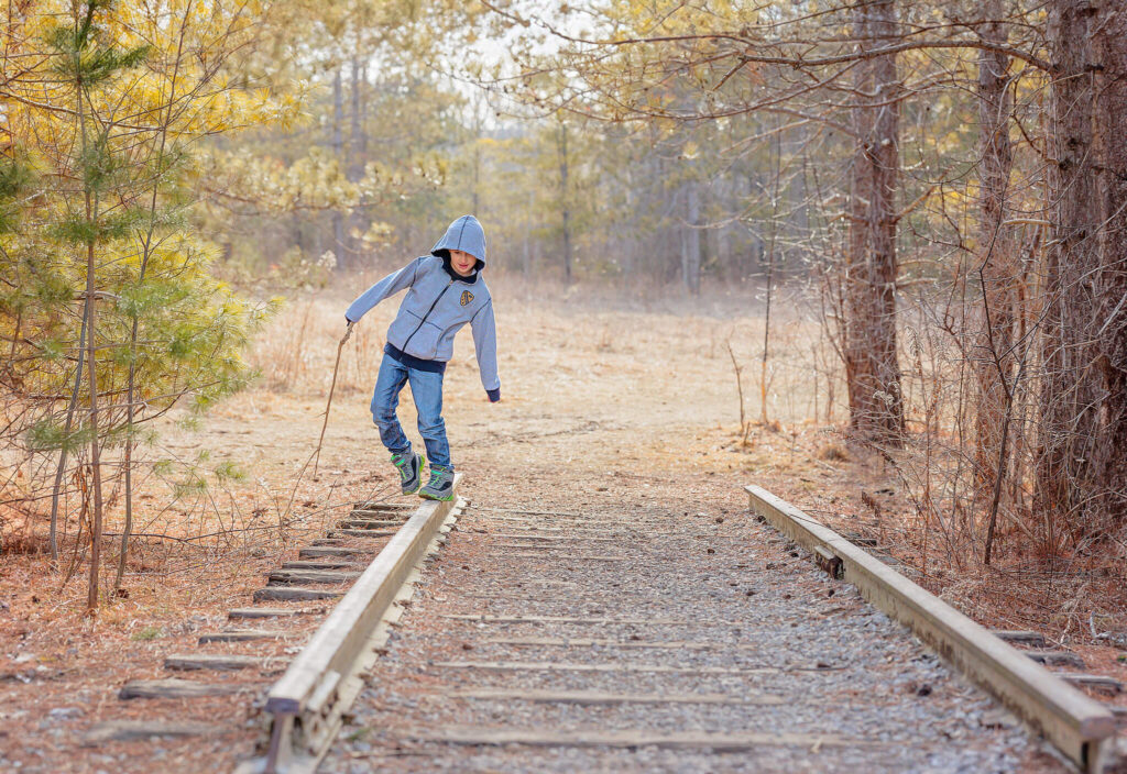 A young boy balancing on old, no longer being used, railroad tracks