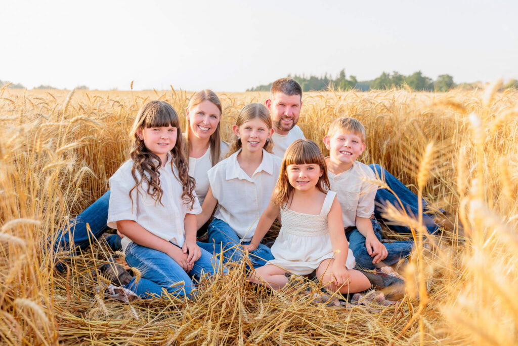 Family sitting together in a wheat field during a relaxed family photography session.