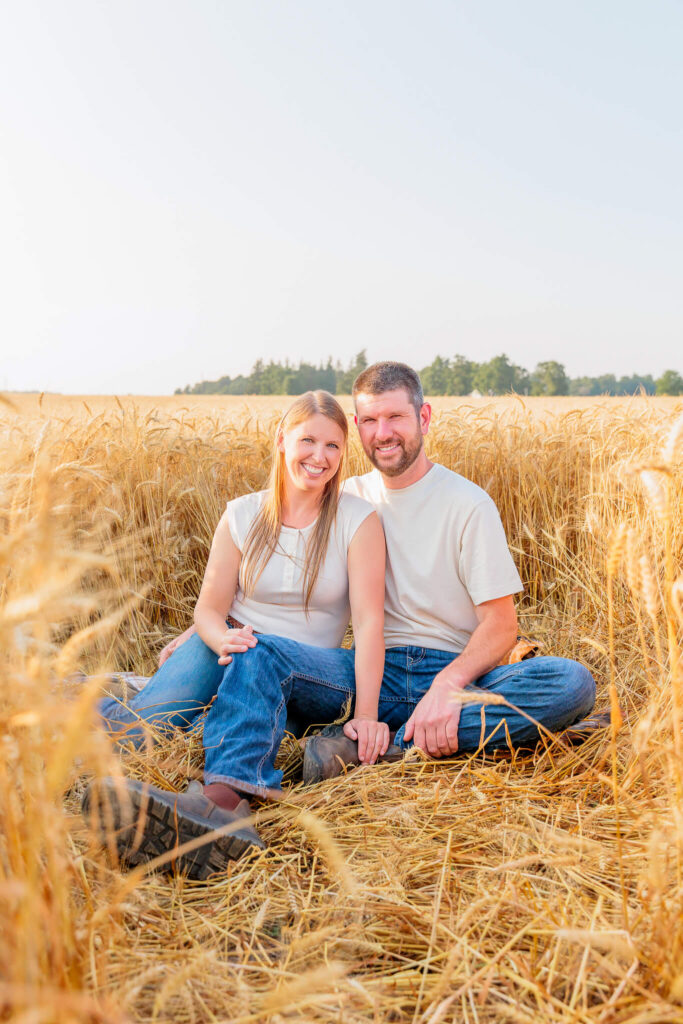 Parents sitting together in a harvested wheat field during a relaxed family photography session.