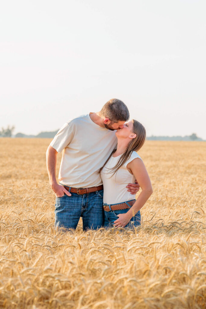 Parents kissing in a wheat field during a beautiful family photography session.